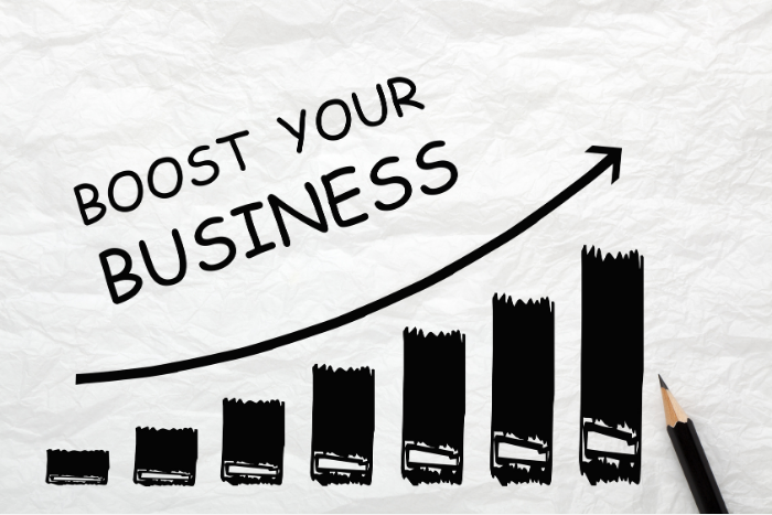 A hand-drawn black bar chart with rising bars and an upward arrow, alongside the words "BOOST YOUR BUSINESS" on crumpled white paper.